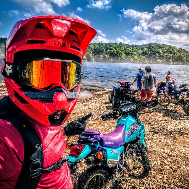 Daniel Bennett in riding gear with dirt bikes by the lake