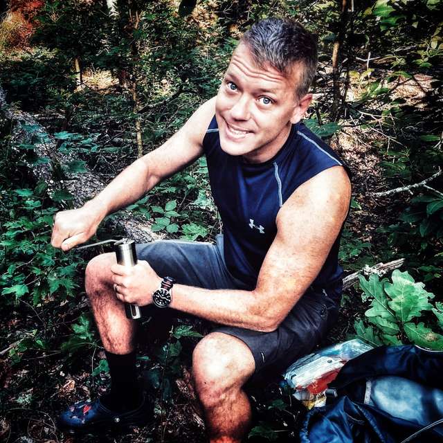 Daniel Bennett making coffee on a wooded trail