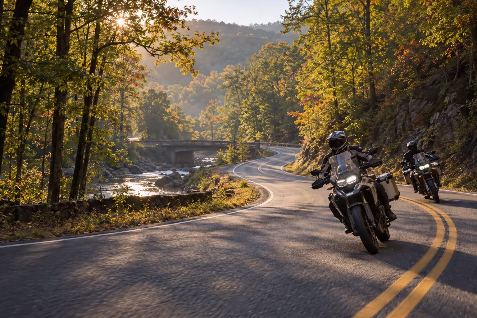 Motorcyclists riding a wooded curve near a creek in western Tennessee